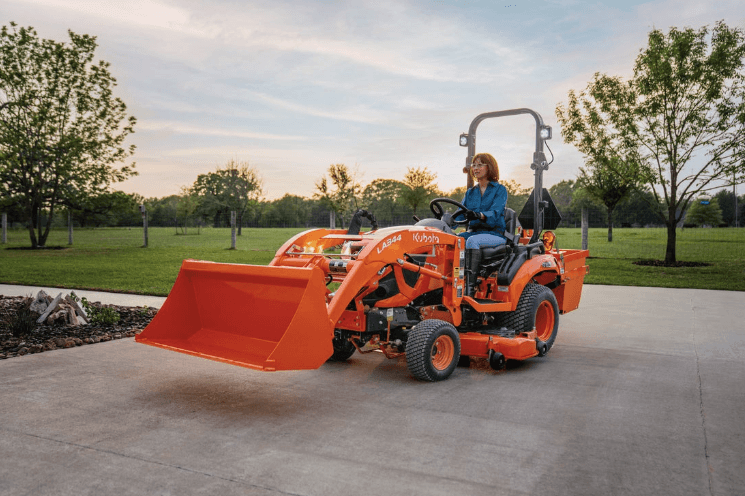 Woman driving Sub-Compact Tractor