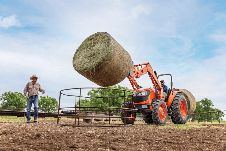 Man moving a hay bale with a Kubota tractor